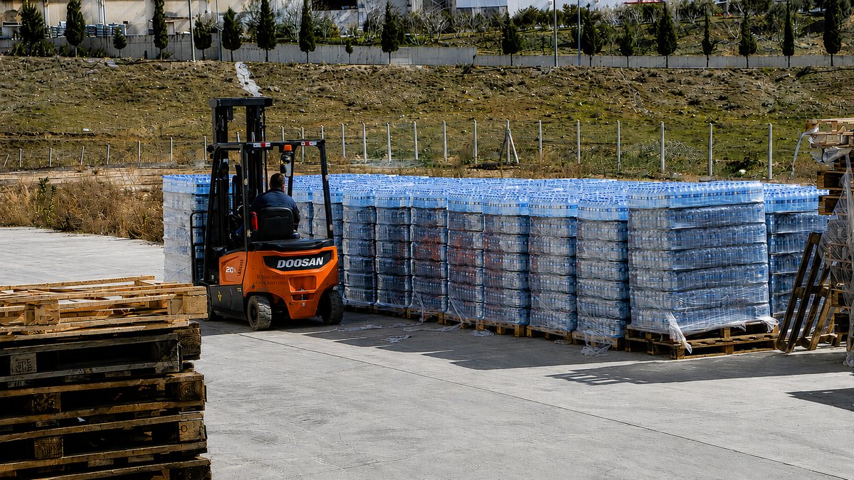 Pallets of bottled water moved by forklift in a plant's dispatch yard