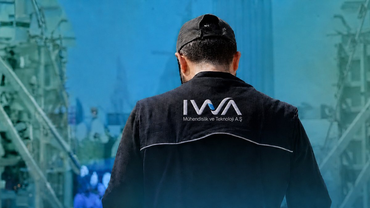 Sırtında IWA Mühendislik ve Teknoloji logosu bulunan saha çalışanı, tesis sahasına bakarken